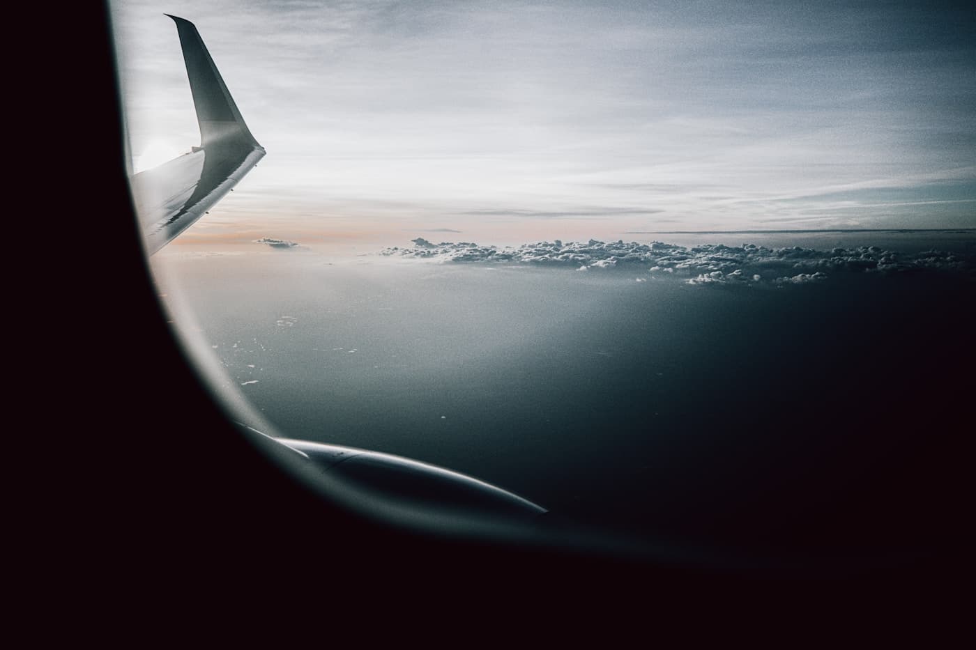 A quiet view of clouds and an aircraft wing through a cabin window