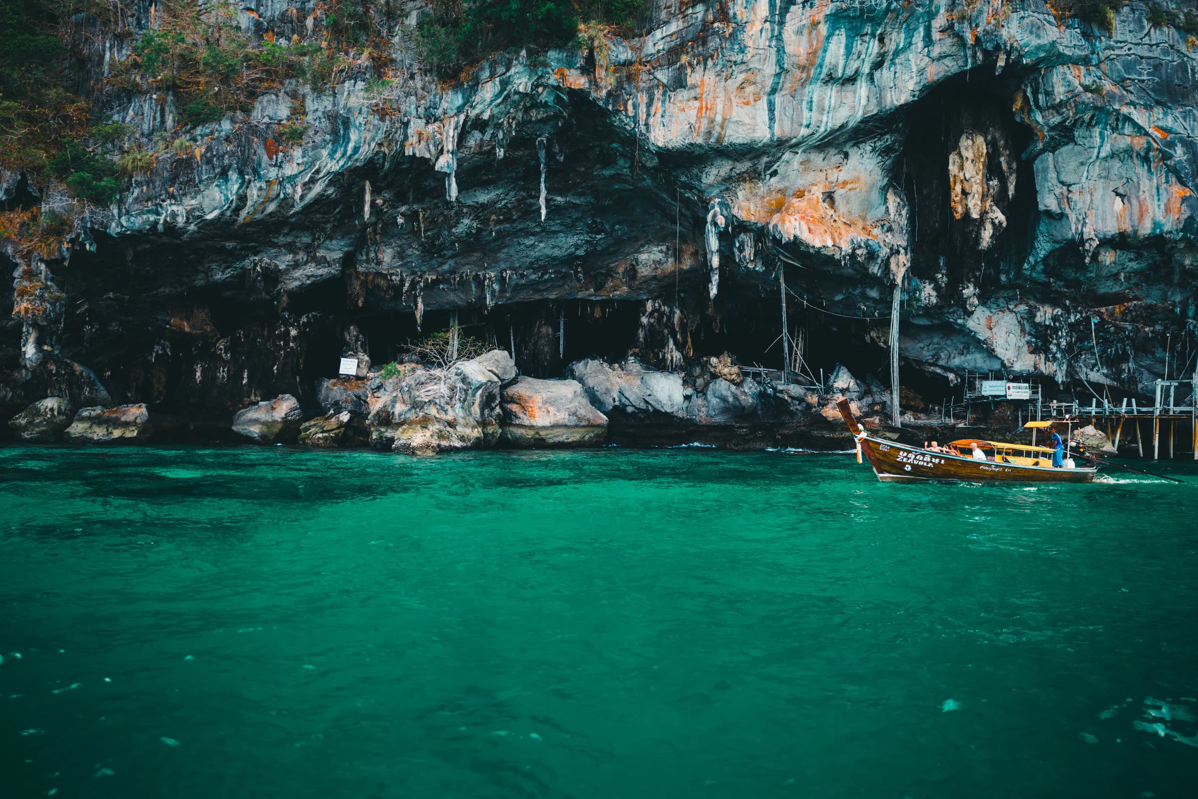 A long-tail boat beneath limestone cliffs in Phuket