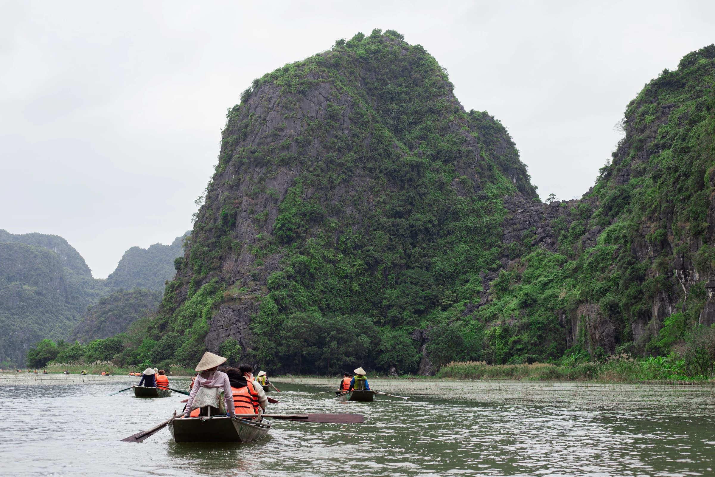 Boats crossing a river beneath limestone peaks in Ninh Binh